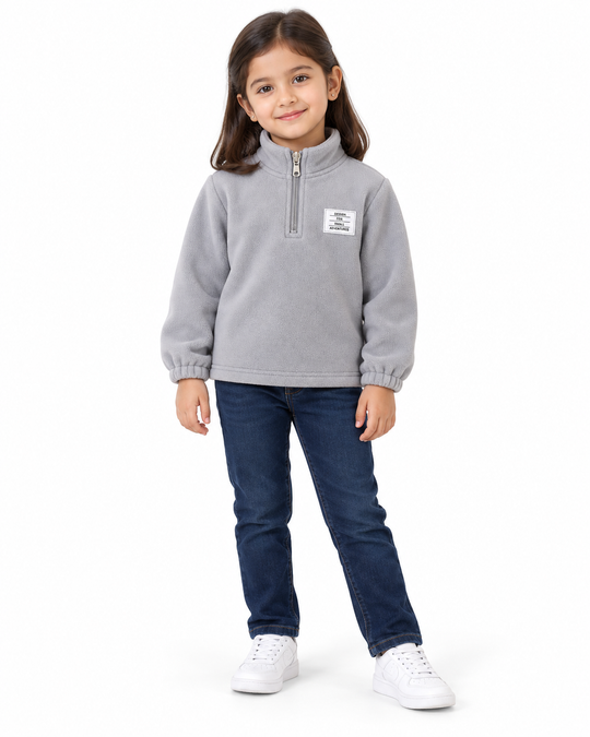 Girl wearing a cloud grey fleece half-zip sweatshirt with dark blue jeans and white sneakers.